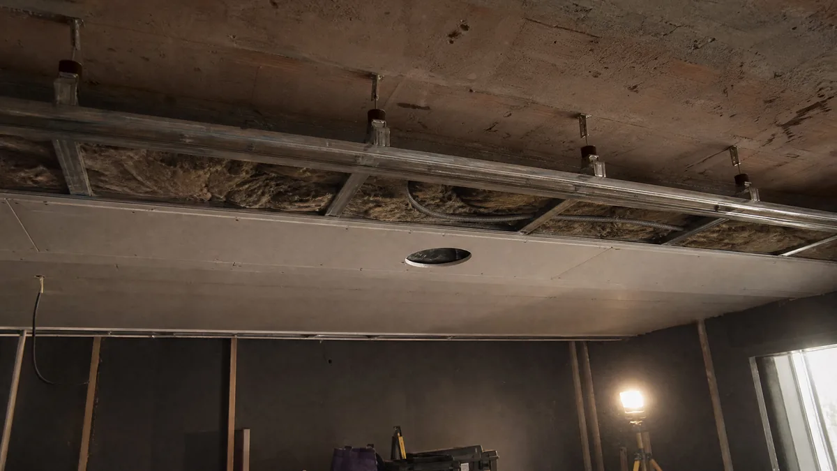 Controsoffitto acustico aperto in cantiere Controsoffitto acustico aperto in cantiere: solaio in cemento, staffe antivibranti, lana minerale nell'intercapedine e doppia lastra in cartongesso con il foro del diffusore a soffitto
